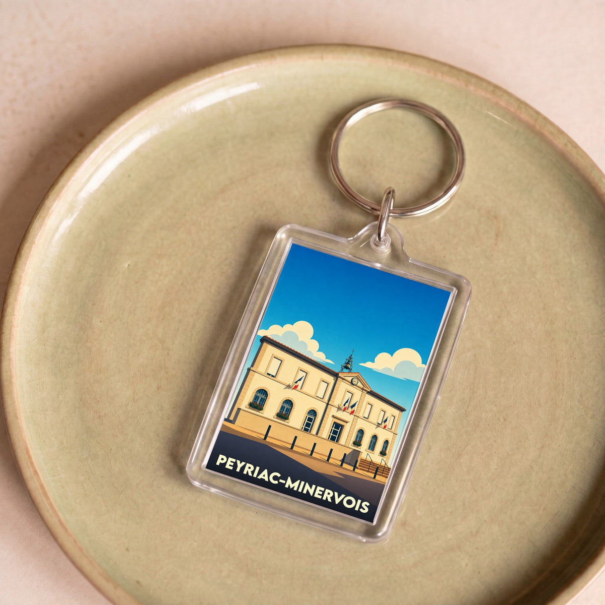 Porte-clés souvenir de la ville de Peyriac-Minervois avec une illustration stylisée de la mairie.