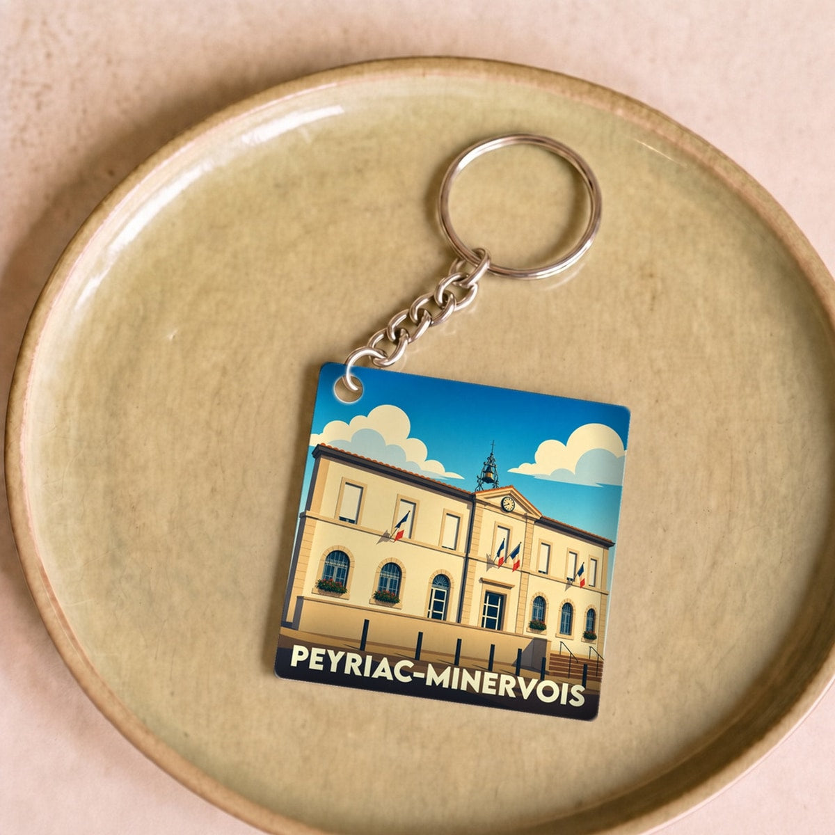 Porte-clés souvenir de la ville de Peyriac-Minervois avec une illustration stylisée de la mairie.