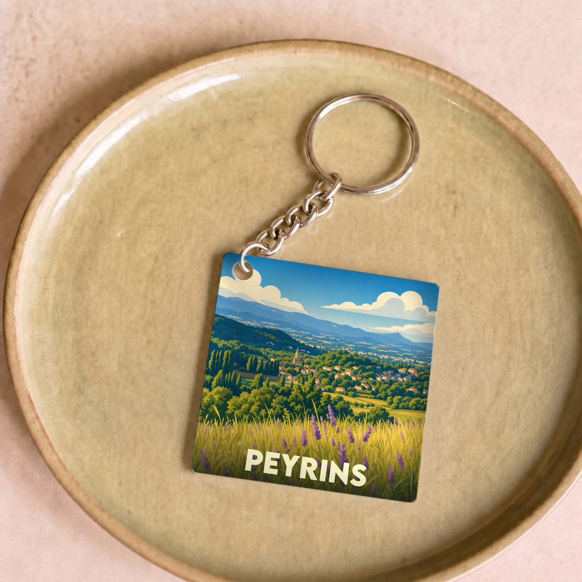 Porte-clés souvenir de la ville de Peyrins avec une illustration stylisée de paysages provençaux.
