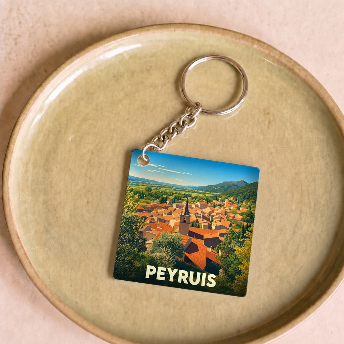 Porte-clés souvenir de la ville de Peyruis avec une illustration stylisée de ses toits provençaux.
