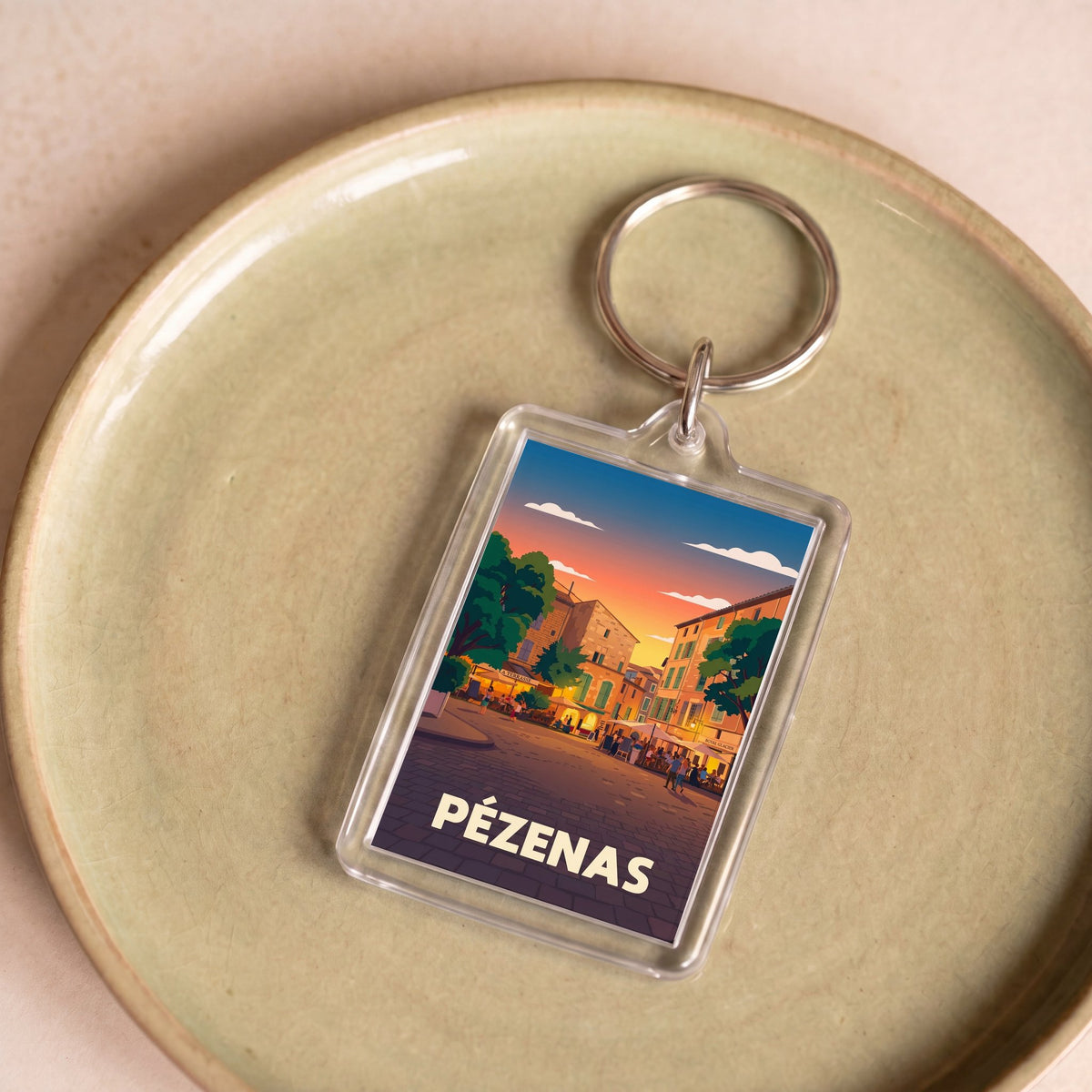 Porte-clés souvenir de la ville de Pézenas avec une illustration stylisée.