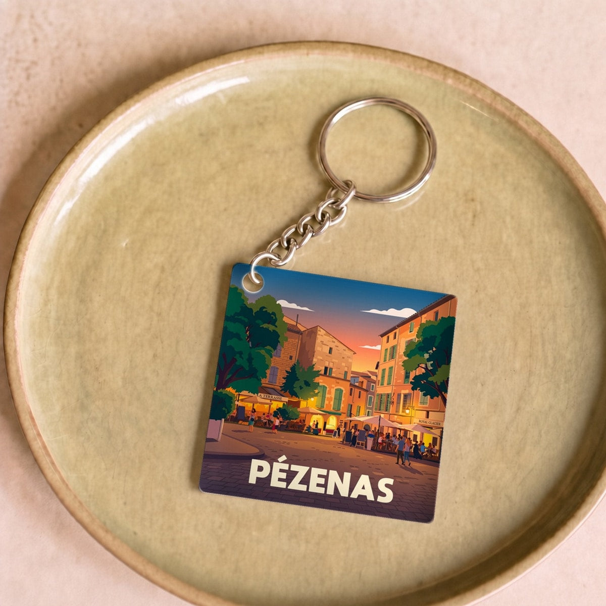 Porte-clés souvenir de la ville de Pézenas avec une illustration stylisée.