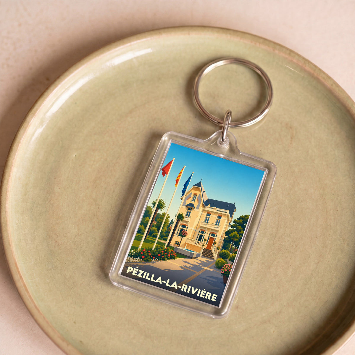 Porte-clés souvenir de la ville de Pézilla-la-Rivière avec une illustration stylisée de sa mairie.