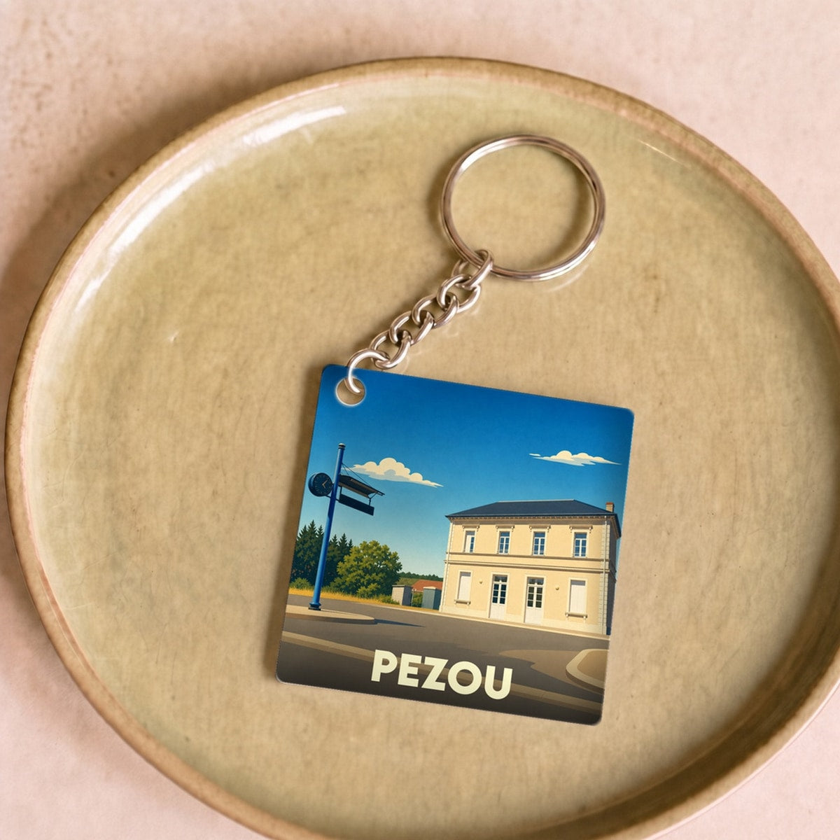 Porte-clés souvenir de la ville de Pezou avec une illustration stylisée.
