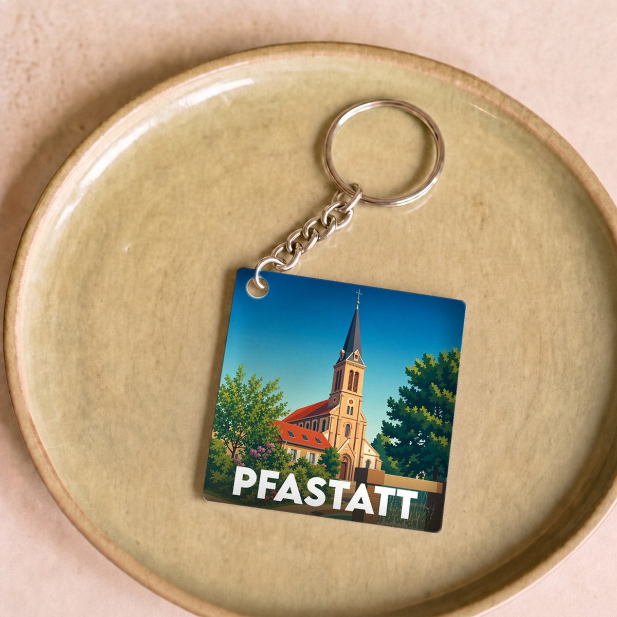 Porte-clés souvenir de la ville de Pfastatt avec une illustration stylisée de son église.