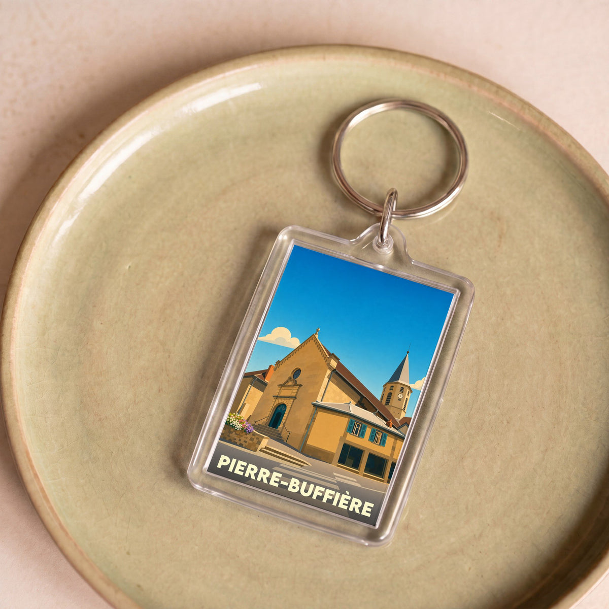 Porte-clés souvenir de la ville de Pierre-Buffière avec une illustration stylisée de son église.