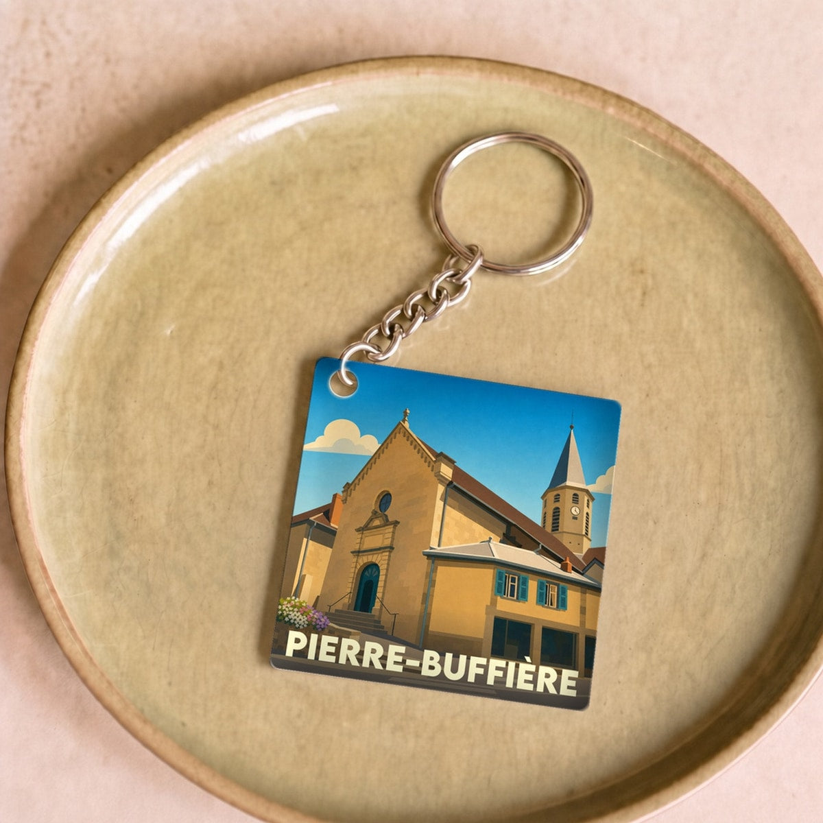 Porte-clés souvenir de la ville de Pierre-Buffière avec une illustration stylisée de son église.