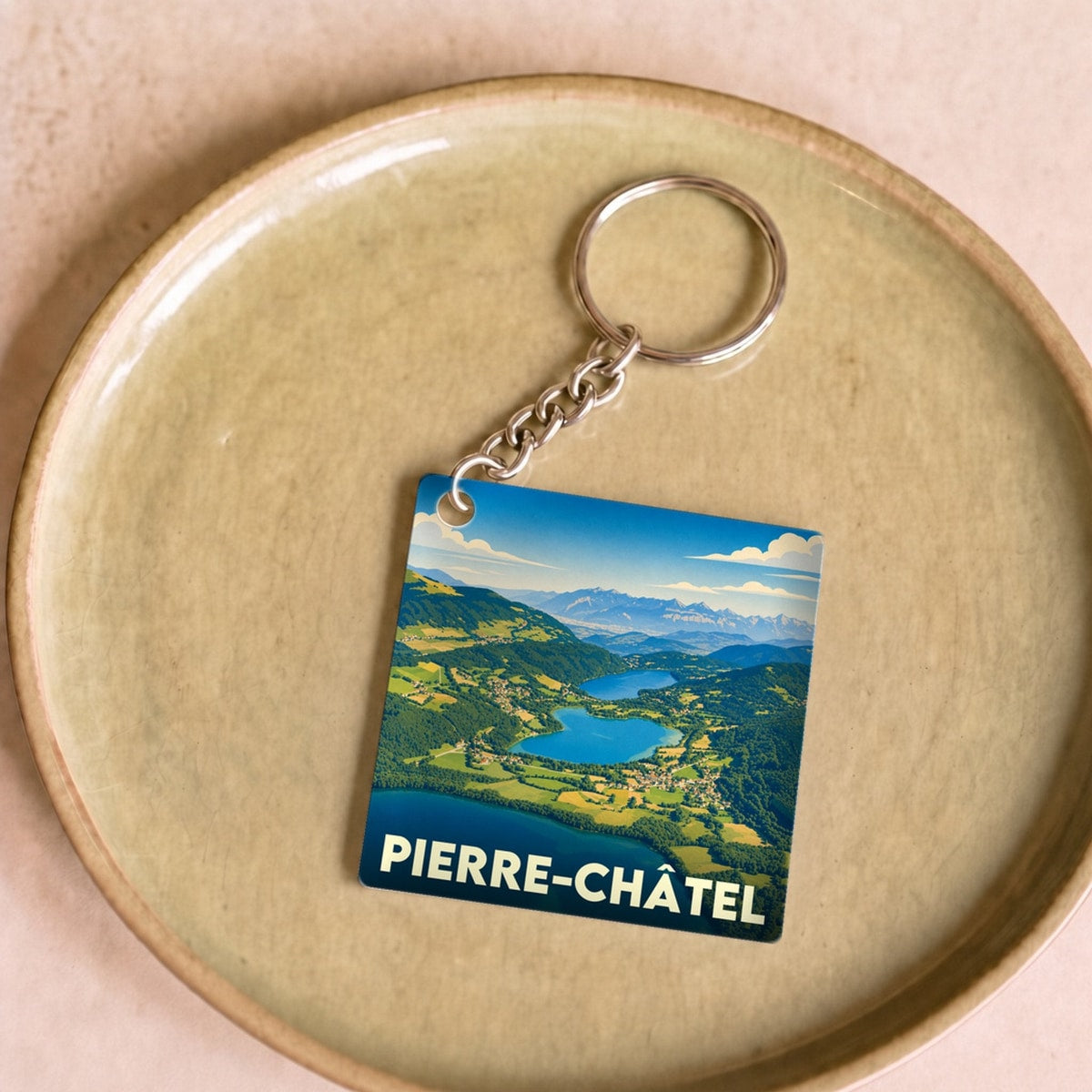 Porte-clés souvenir de la ville de Pierre-Châtel avec une illustration stylisée de ses lacs et montagnes.