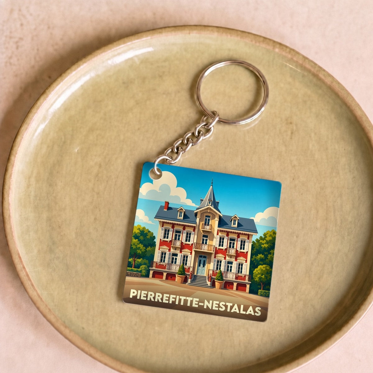 Porte-clés souvenir de la ville de Pierrefitte-Nestalas avec une illustration stylisée d'une bâtisse historique.