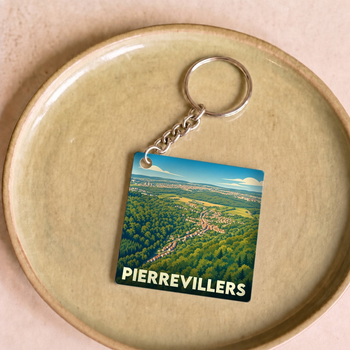 Porte-clés souvenir de la ville de Pierrevillers avec une illustration stylisée de son paysage verdoyant.