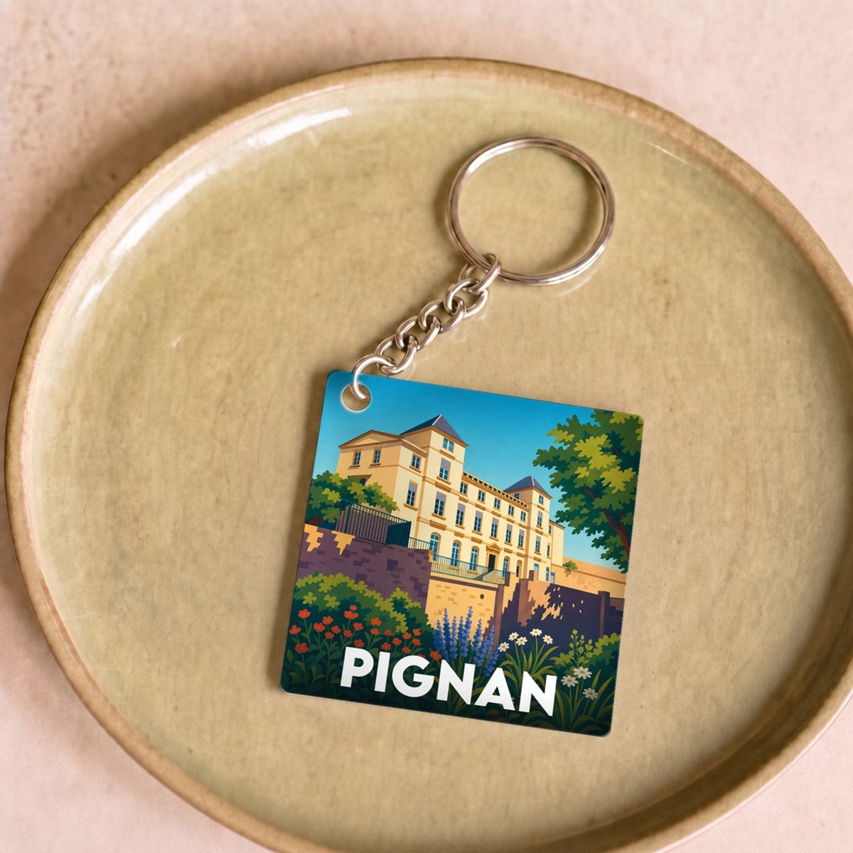 Porte-clés souvenir de la ville de Pignan avec une illustration stylisée.