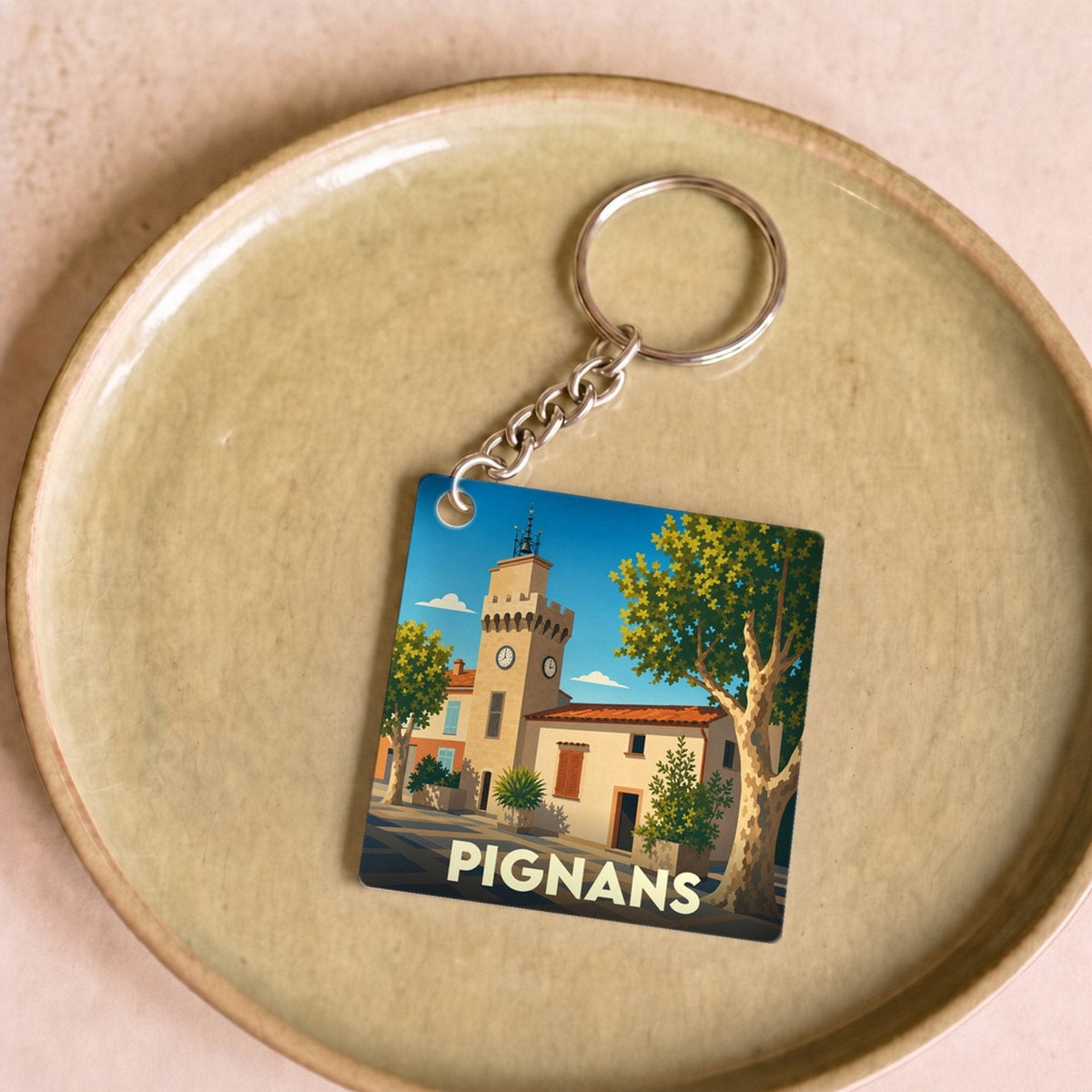 Porte-clés souvenir de la ville de Pignans avec une illustration stylisée.
