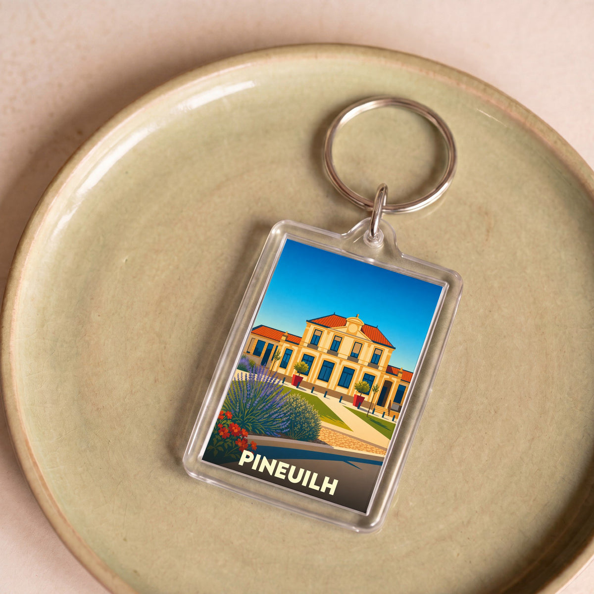 Porte-clés souvenir de la ville de Pineuilh avec une illustration stylisée de sa mairie.