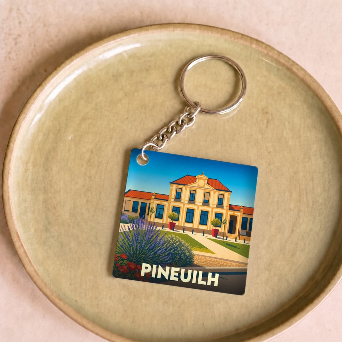 Porte-clés souvenir de la ville de Pineuilh avec une illustration stylisée de sa mairie.