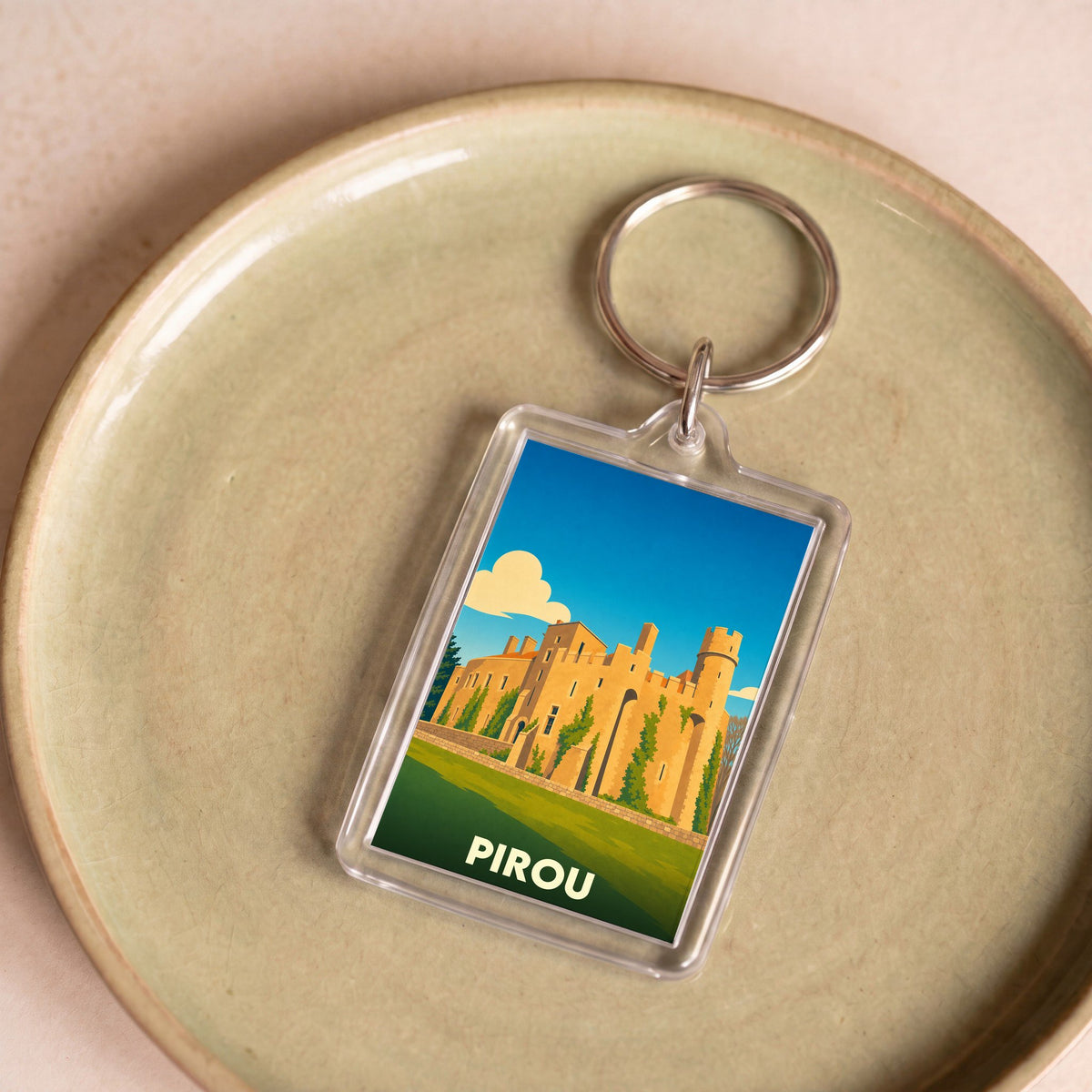 Porte-clés souvenir de la ville de Pirou avec une illustration stylisée de son château.