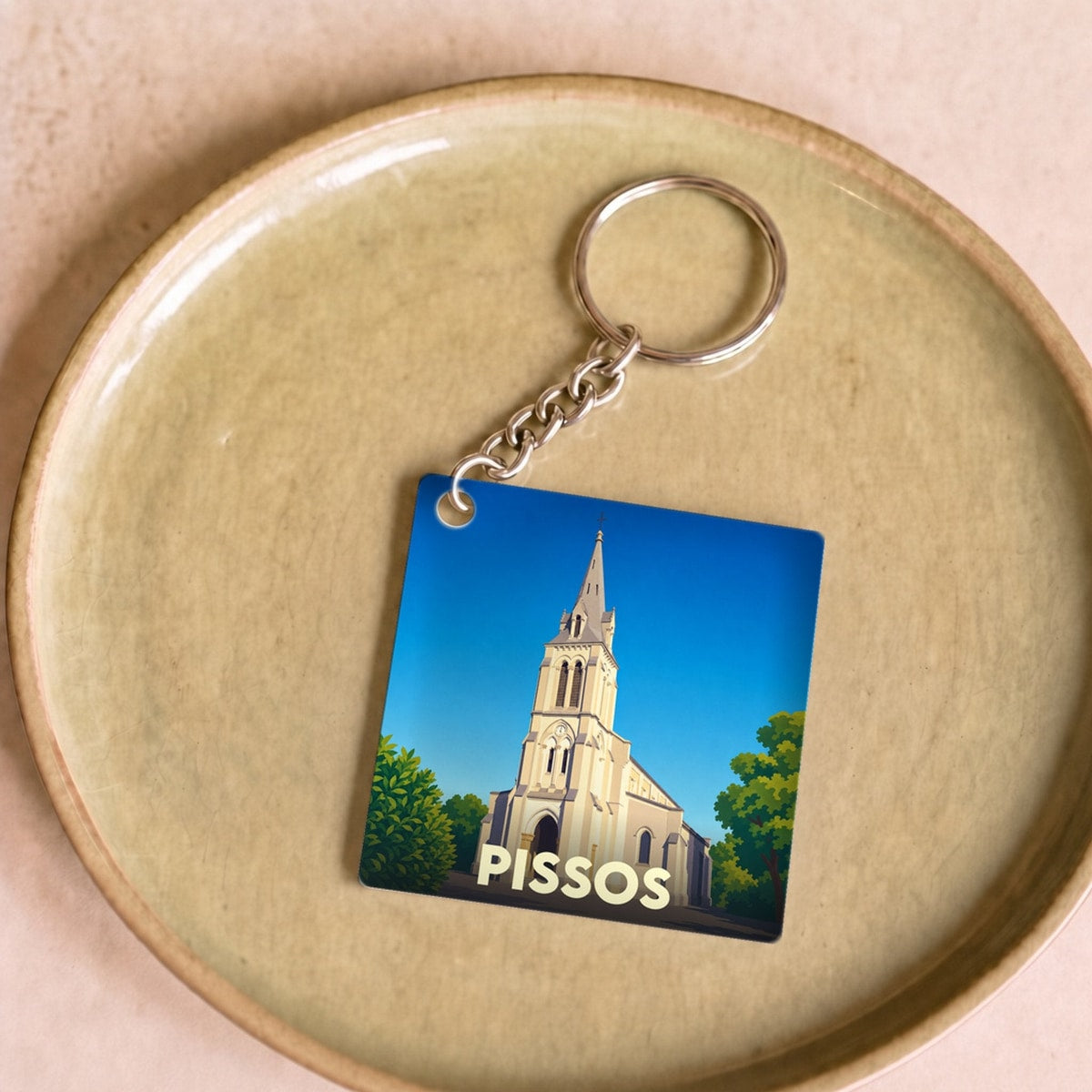 Porte-clés souvenir de la ville de Pissos avec une illustration stylisée de son église.