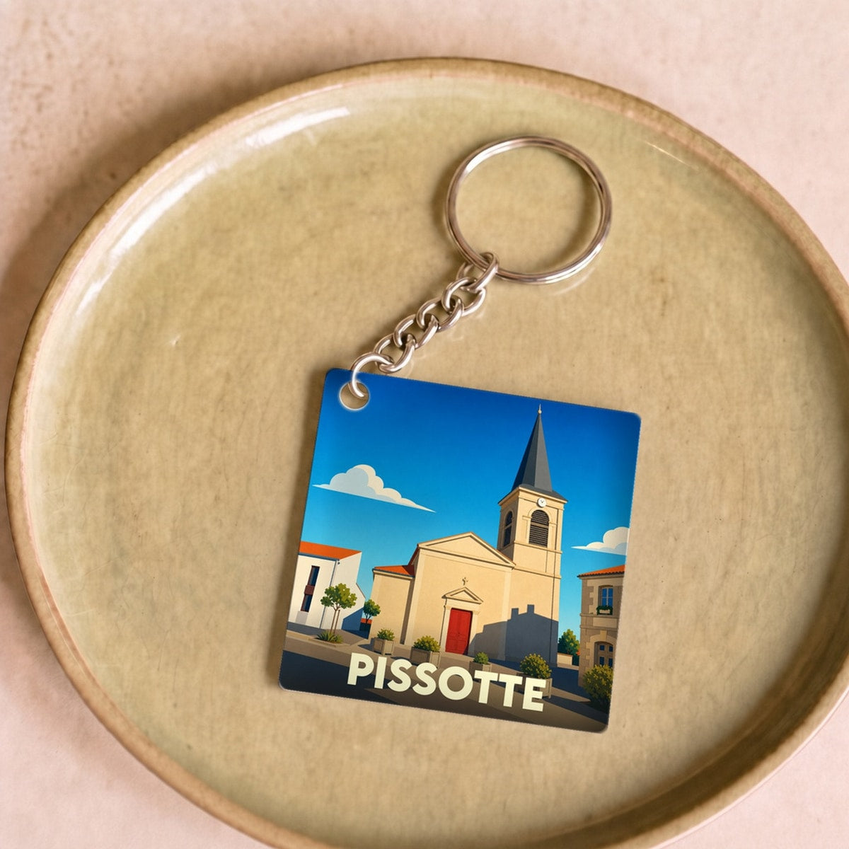 Porte-clés souvenir de la ville de Pissotte avec une illustration stylisée de son église.