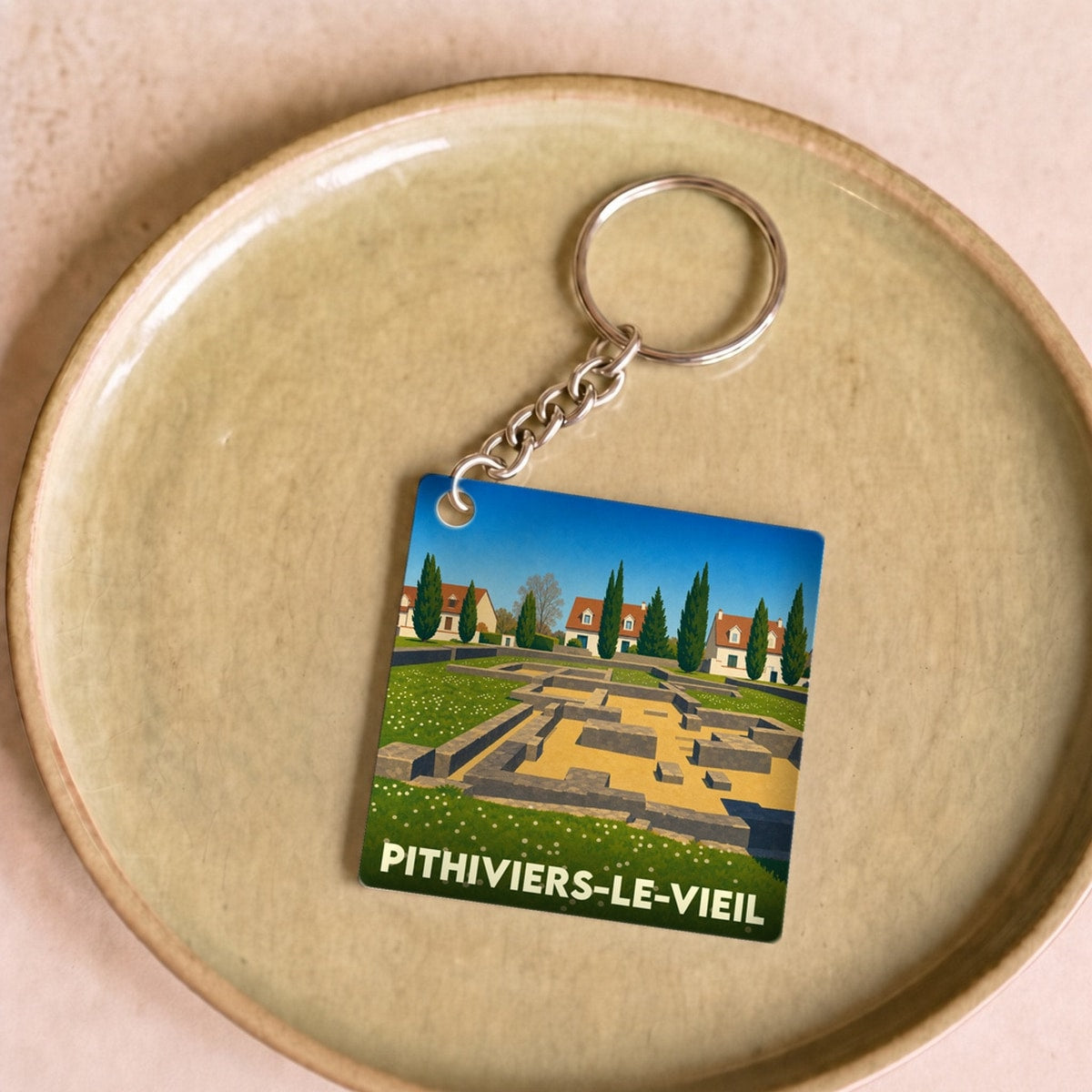 Porte-clés souvenir de la ville de Pithiviers-le-Vieil avec une illustration stylisée de vestiges archéologiques.