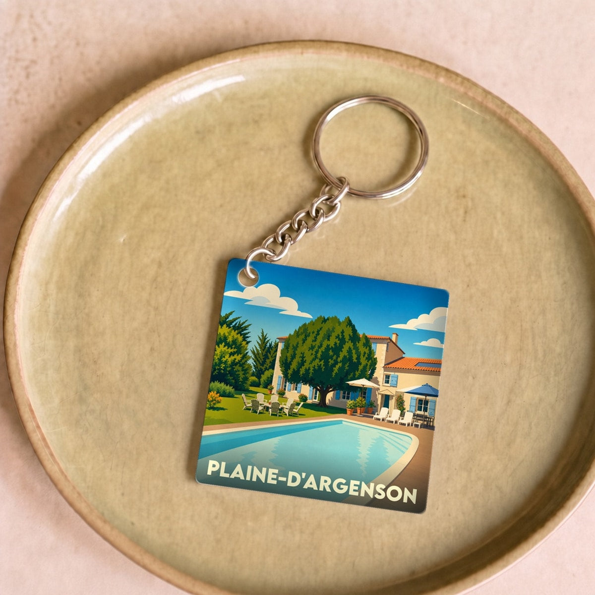 Porte-clés souvenir de la ville de Plaine-d'Argenson avec une illustration stylisée d'une villa et sa piscine.