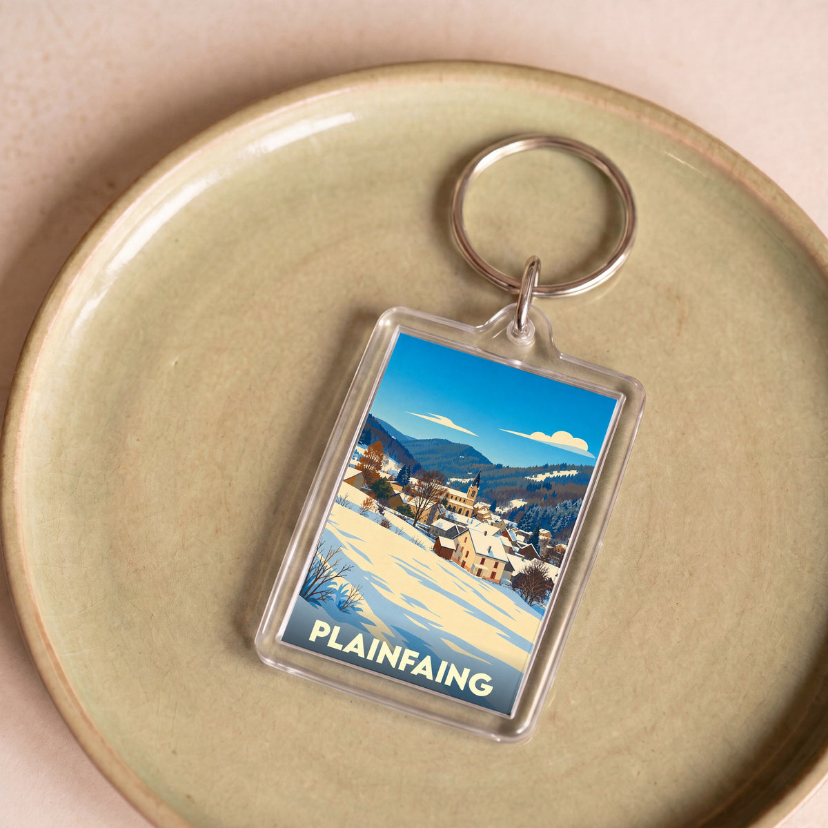 Porte-clés souvenir de la ville de Plainfaing avec une illustration hivernale stylisée.