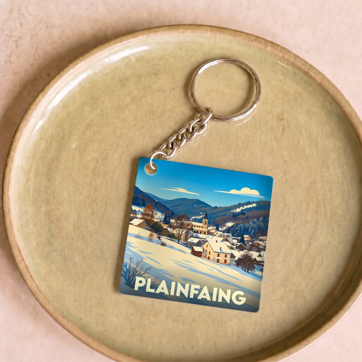 Porte-clés souvenir de la ville de Plainfaing avec une illustration hivernale stylisée.