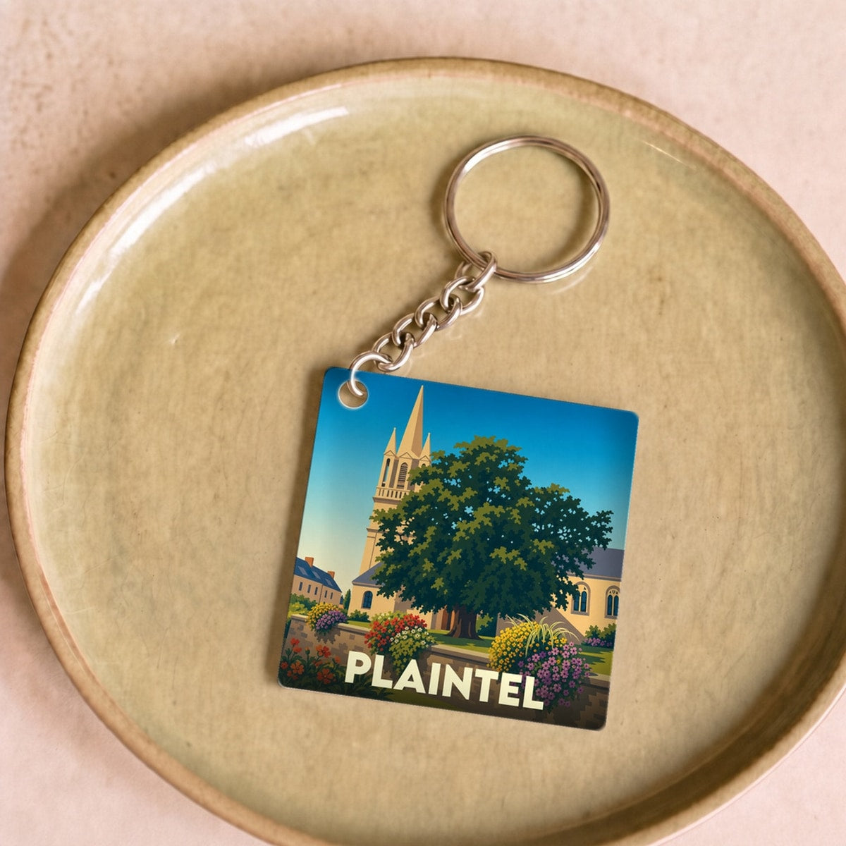 Porte-clés souvenir de la ville de Plaintel avec une illustration stylisée.