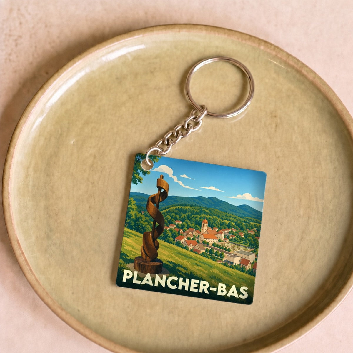 Porte-clés souvenir de la ville de Plancher-Bas avec une illustration stylisée d'un paysage vallonné.