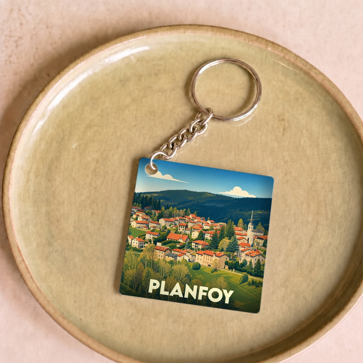 Porte-clés souvenir de la ville de Planfoy avec une illustration stylisée.