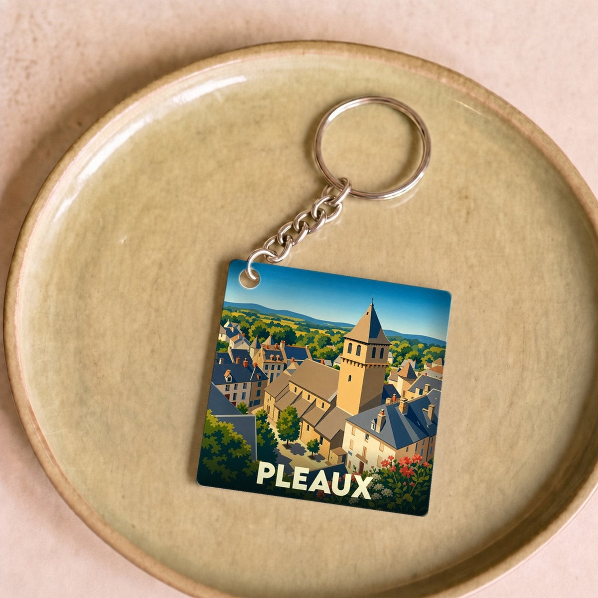 Porte-clés souvenir de la ville de Pleaux avec une illustration stylisée.