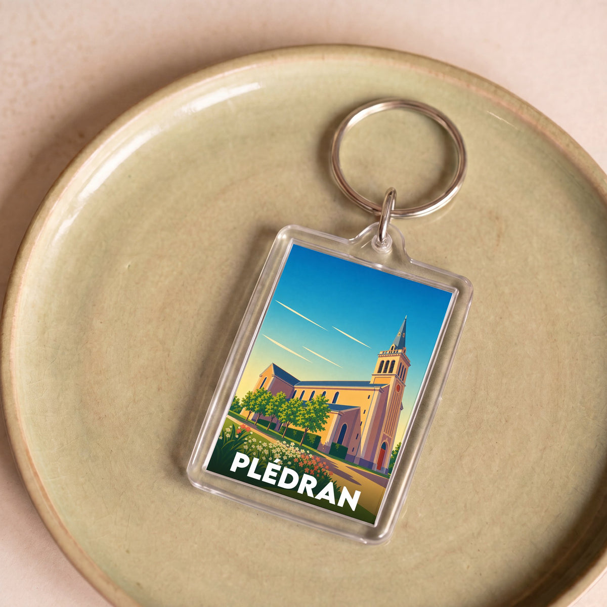Porte-clés souvenir de la ville de Plédran avec une illustration stylisée de son église.