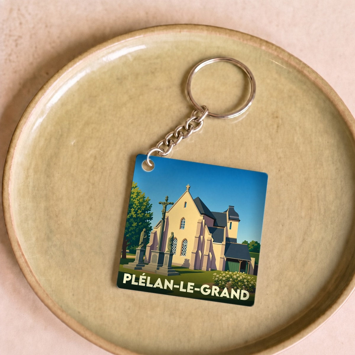 Porte-clés souvenir de la ville de Plélan-le-Grand avec une illustration stylisée de son église.