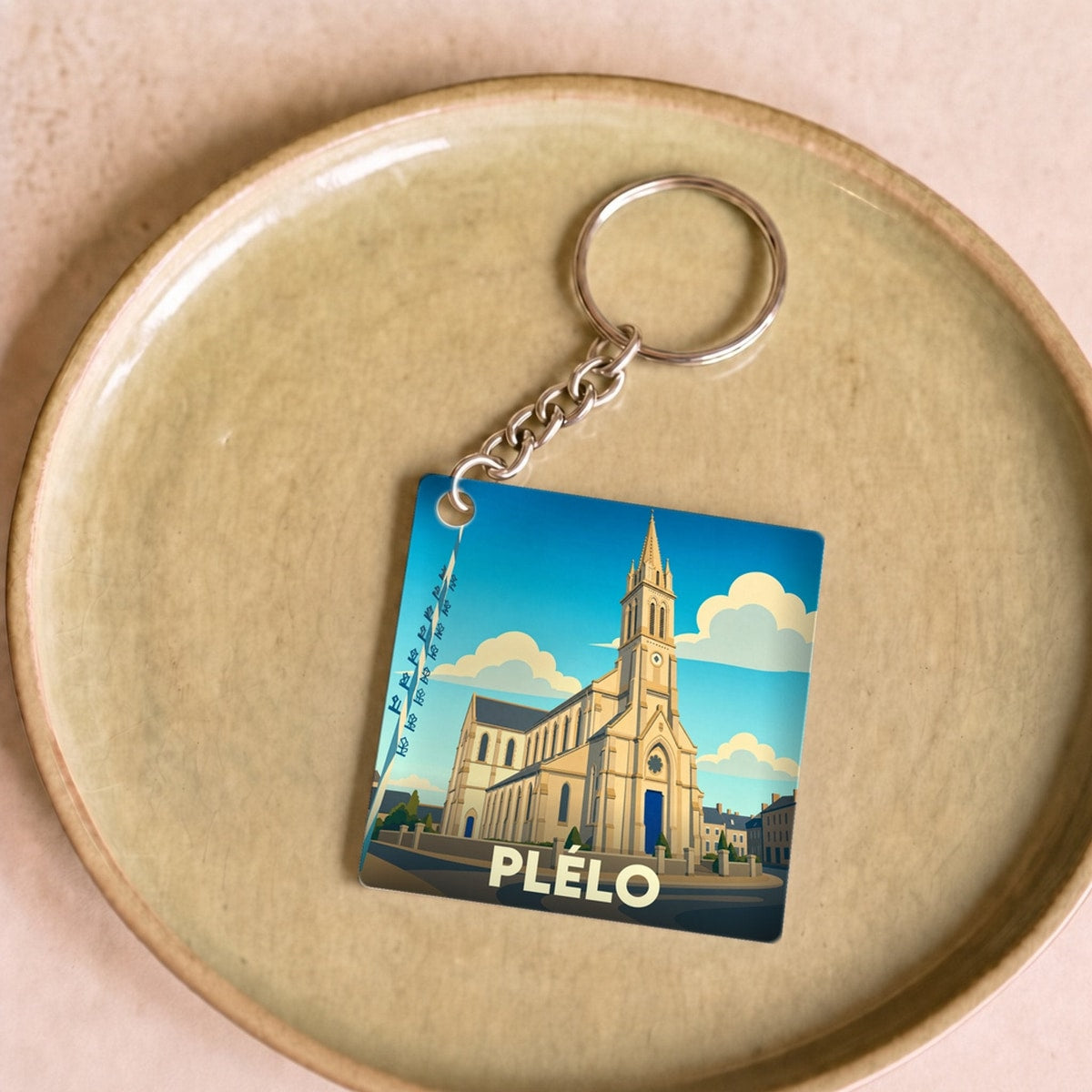 Porte-clés souvenir de la ville de Plélo avec une illustration stylisée de son église.