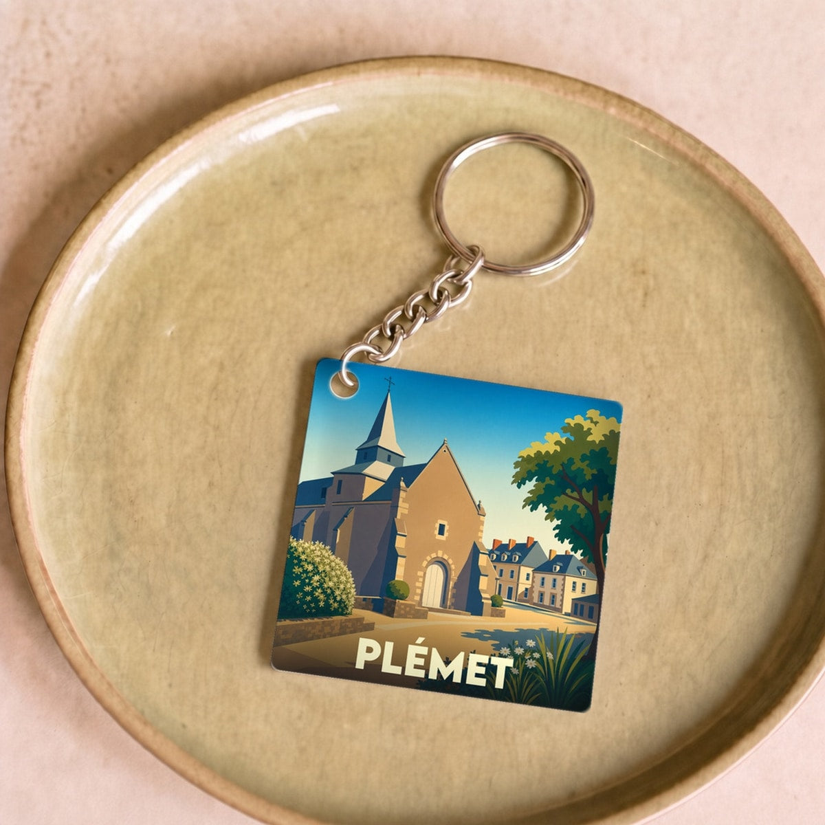 Porte-clés souvenir de la ville de Plémet avec une illustration stylisée.