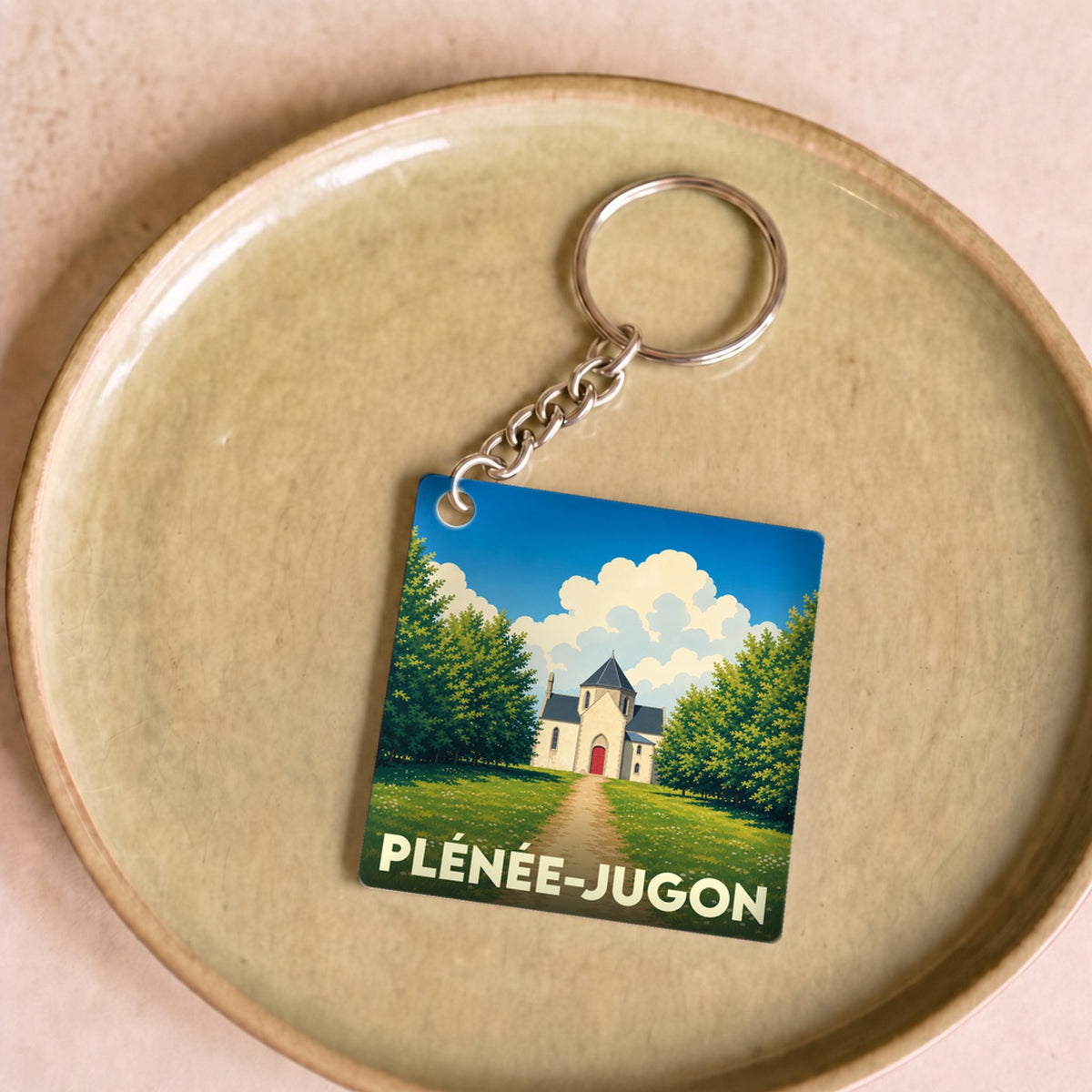 Porte-clés souvenir de la ville de Plénée-Jugon avec une illustration stylisée.