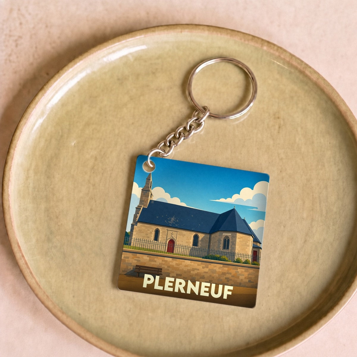 Porte-clés souvenir de la ville de Plerneuf avec une illustration stylisée de son église.
