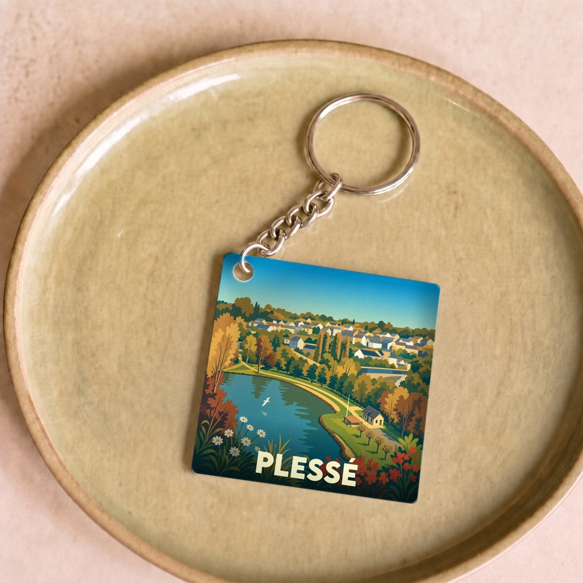 Porte-clés souvenir de la ville de Plessé avec une illustration stylisée d'un paysage local.