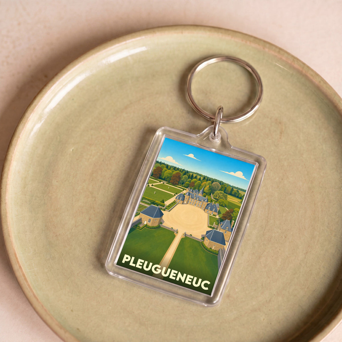 Porte-clés souvenir de la ville de Pleugueneuc avec une illustration stylisée de son château.