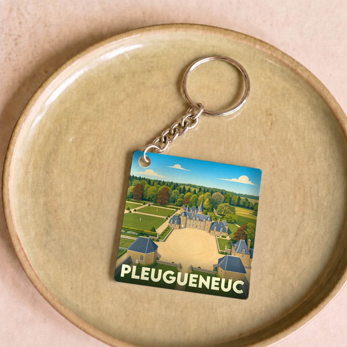 Porte-clés souvenir de la ville de Pleugueneuc avec une illustration stylisée de son château.