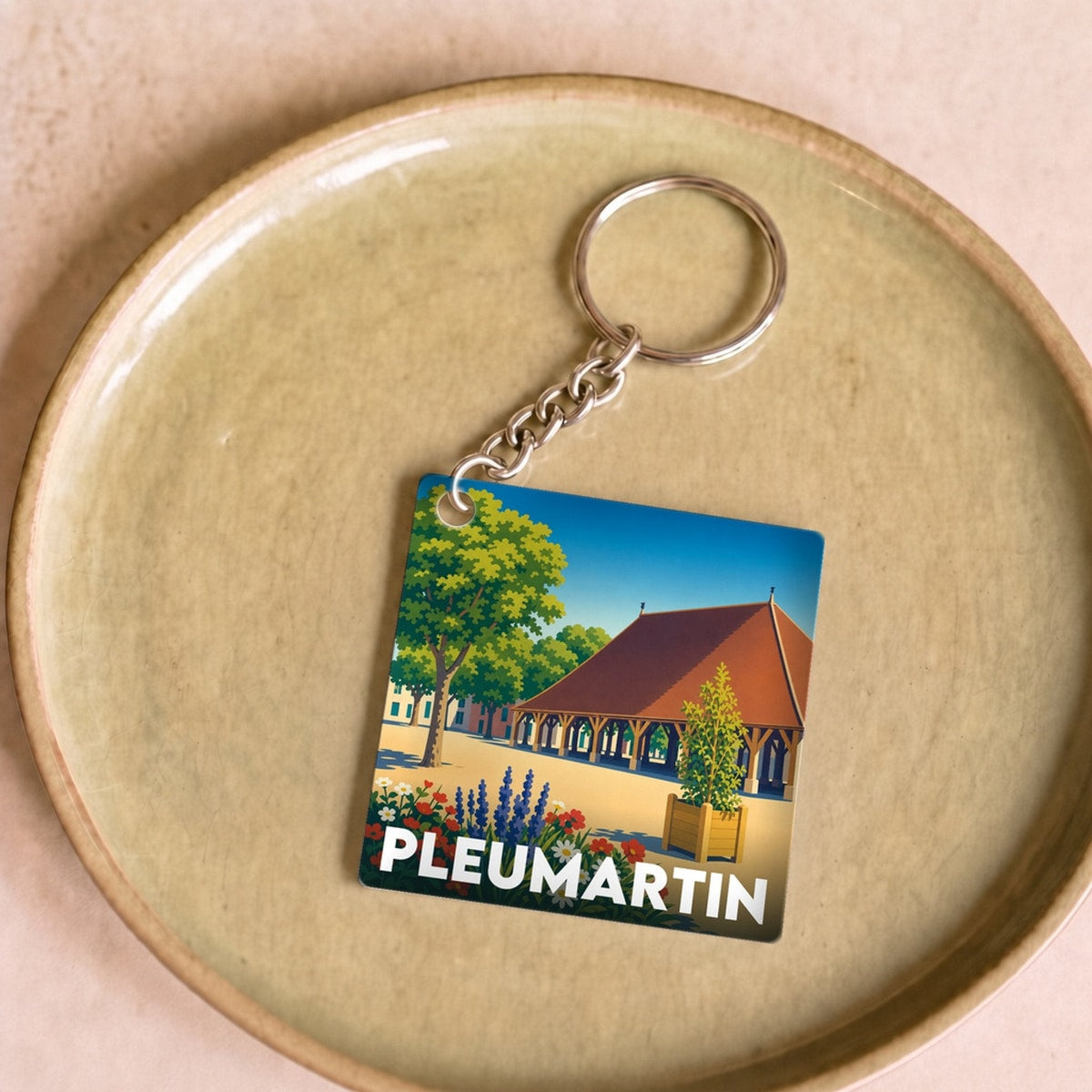 Porte-clés souvenir de la ville de Pleumartin avec une illustration stylisée.