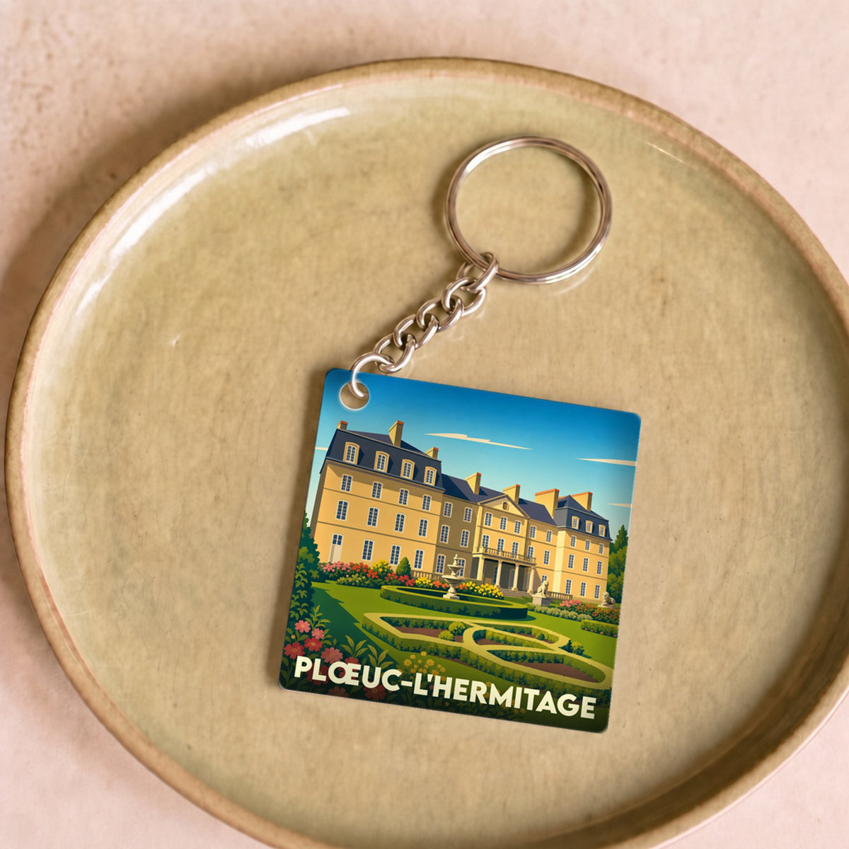 Porte-clés souvenir de la ville de Plœuc-L'Hermitage avec une illustration stylisée d'un château.