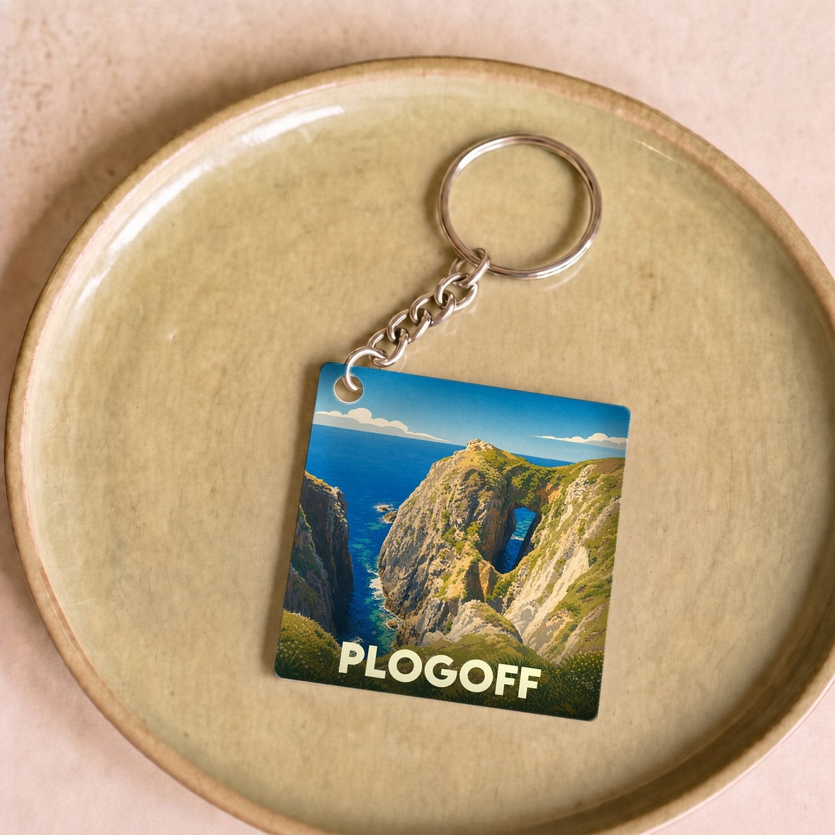 Porte-clés souvenir de la ville de Plogoff avec une illustration stylisée d'un paysage côtier.