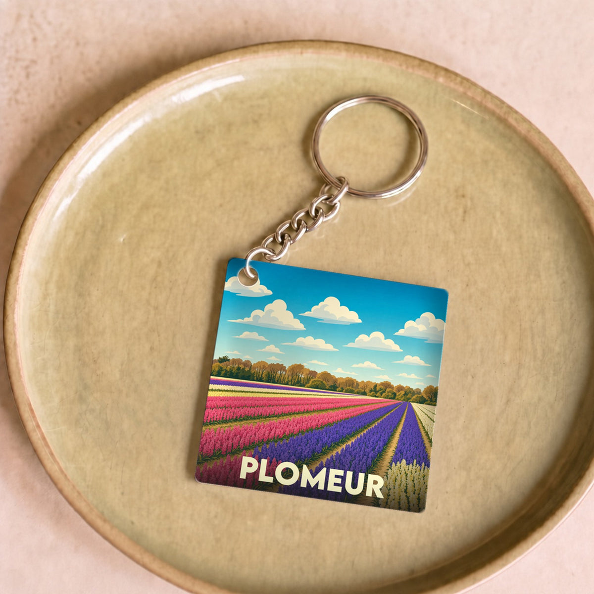 Porte-clés souvenir de la ville de Plomeur avec une illustration stylisée de champs de fleurs colorés.