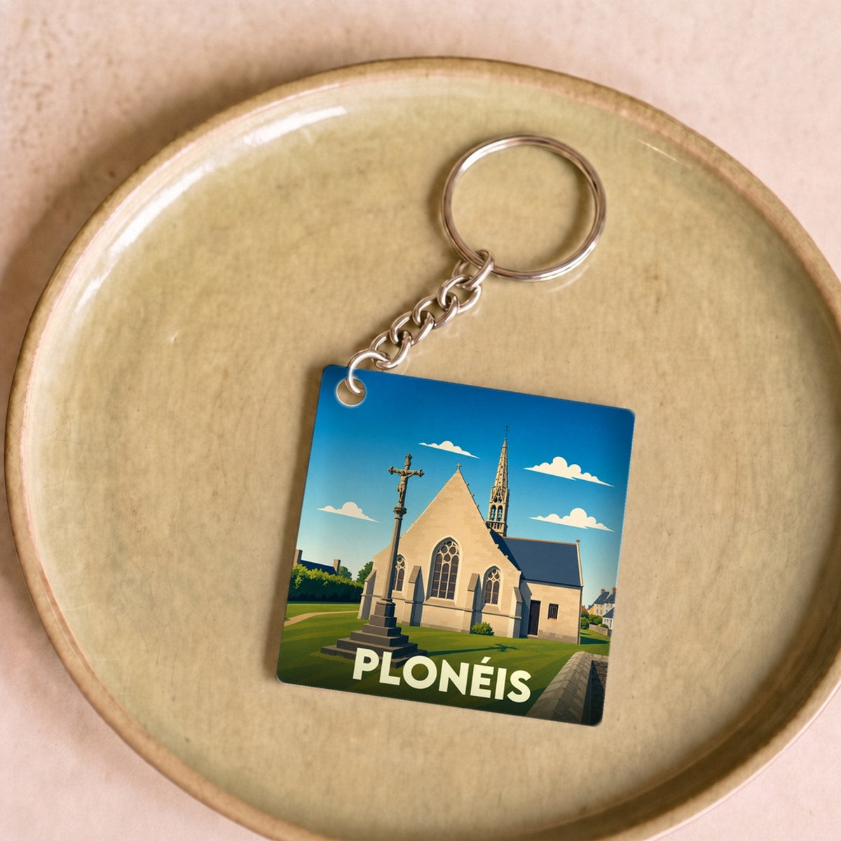 Porte-clés souvenir de la ville de Plonéis avec une illustration stylisée de son église et de son calvaire.