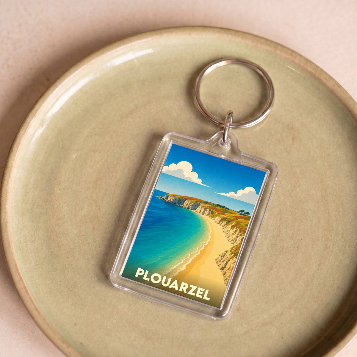 Porte-clés souvenir de la ville de Plouarzel avec une illustration stylisée d'une plage bordée de falaises.