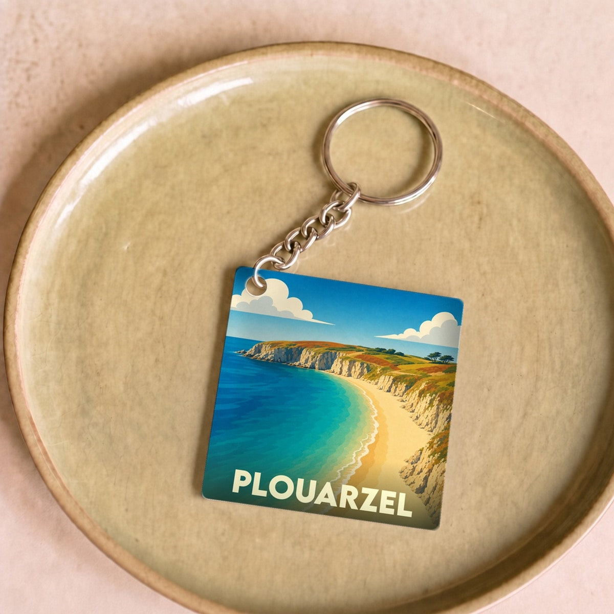 Porte-clés souvenir de la ville de Plouarzel avec une illustration stylisée d'une plage bordée de falaises.