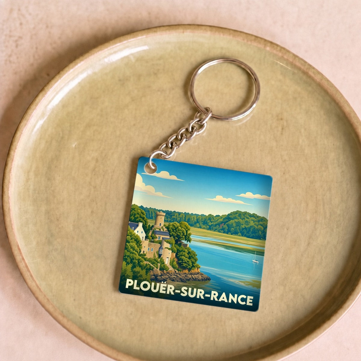 Porte-clés souvenir de la ville de Plouër-sur-Rance avec une illustration stylisée.