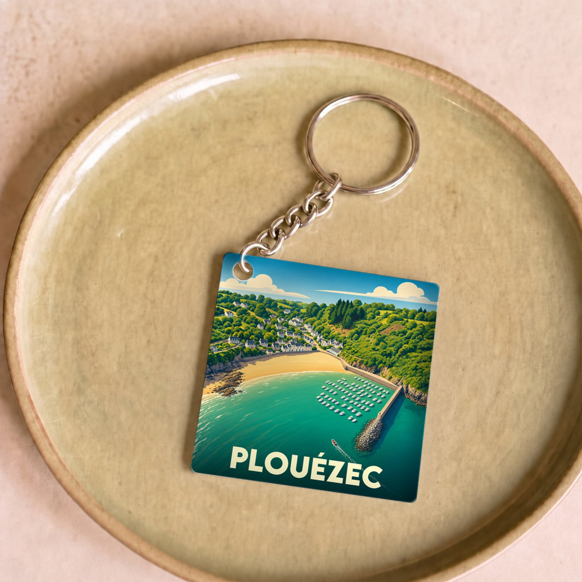 Porte-clés souvenir de la ville de Plouézec avec une illustration stylisée de sa côte et de son port.