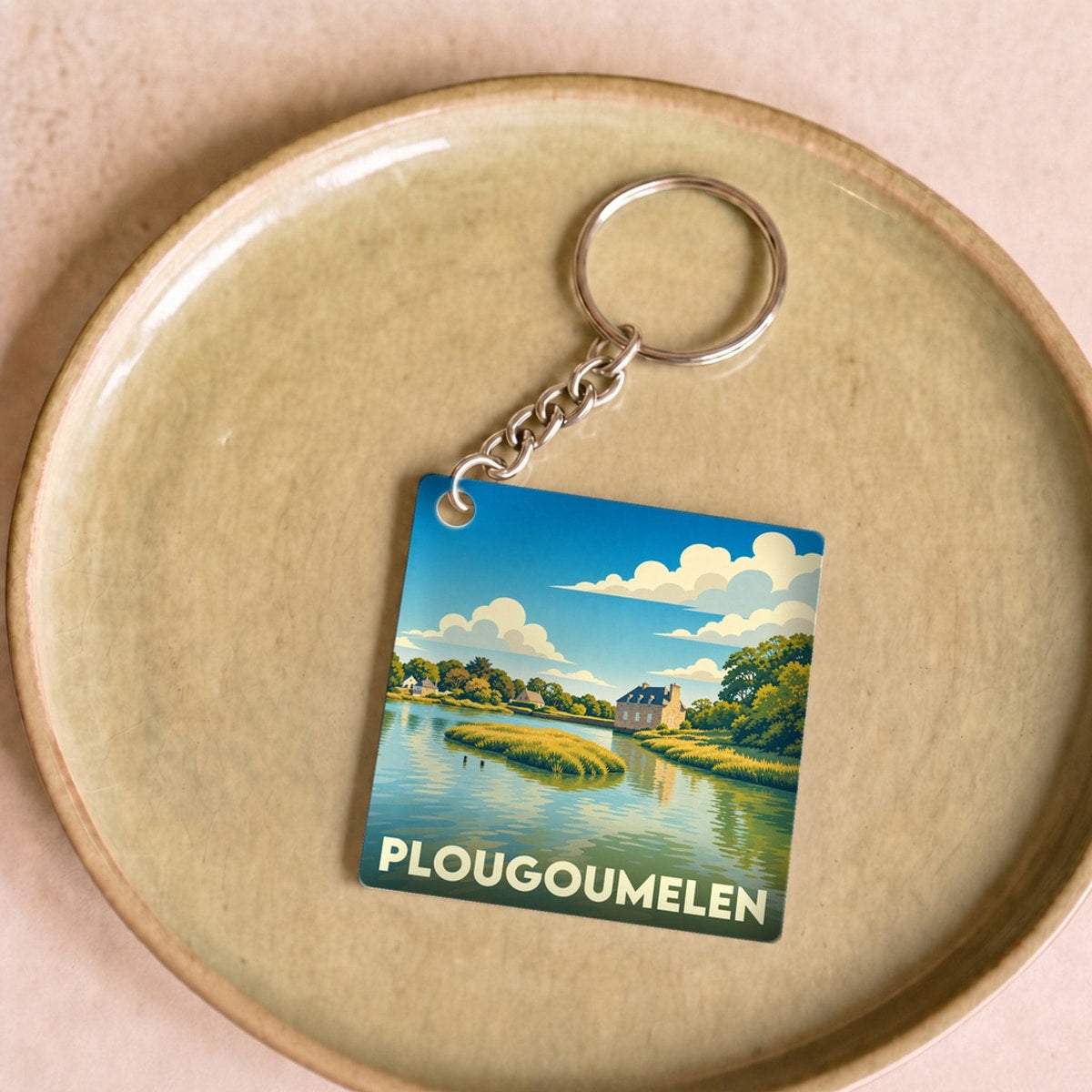 Porte-clés souvenir de la ville de Plougoumelen avec une illustration stylisée d'un paysage côtier.