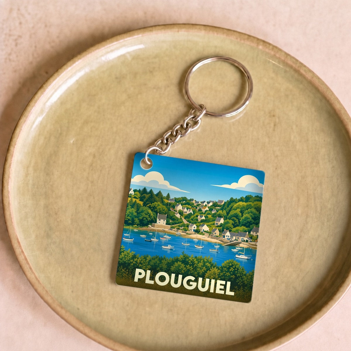 Porte-clés souvenir de la ville de Plouguiel avec une illustration stylisée d'un port côtier.