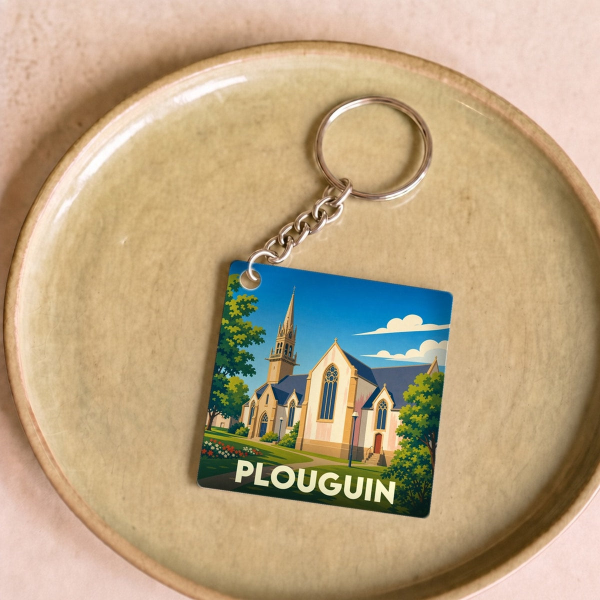 Porte-clés souvenir de la ville de Plouguin avec une illustration stylisée de son église.